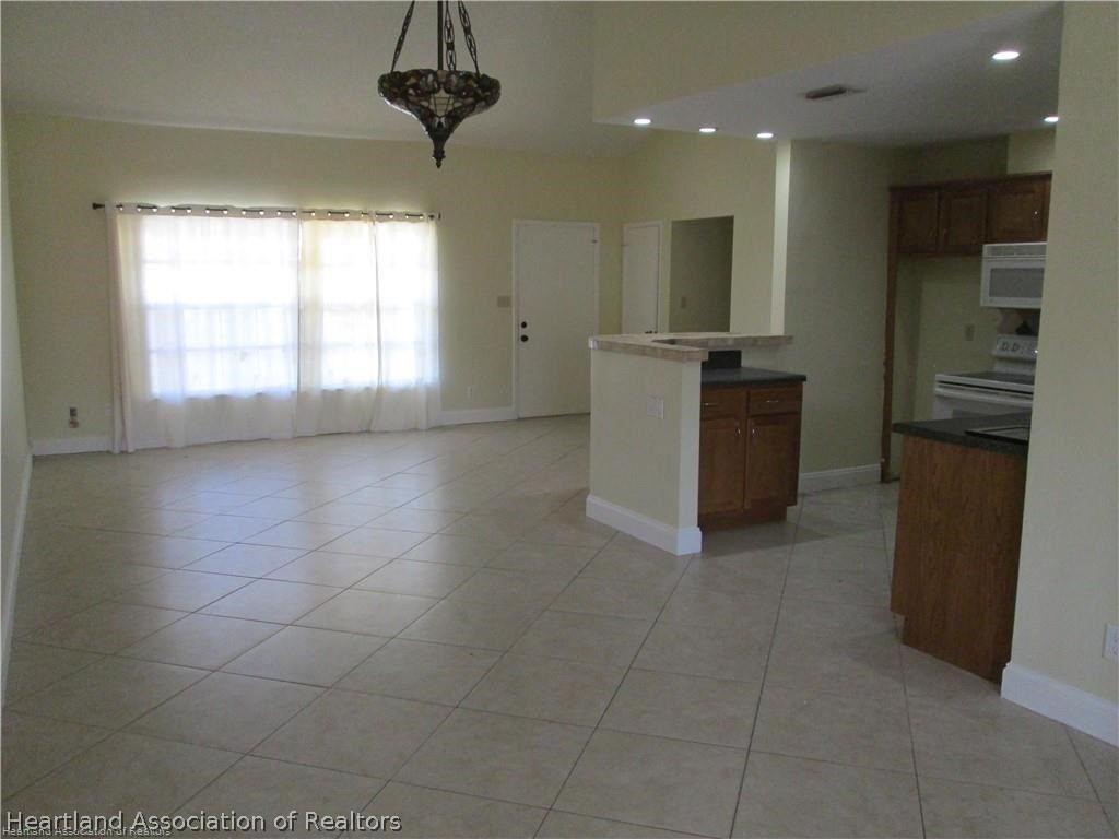 3062 Orchid Road Lake Placid, FL 33852 - Photo 4 of 11 a view of a kitchen with kitchen island stainless steel appliances a sink a counter top space cabinets and a window