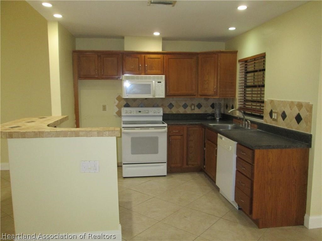3062 Orchid Road Lake Placid, FL 33852 - Photo 5 of 11 a kitchen with stainless steel appliances granite countertop a sink stove and refrigerator