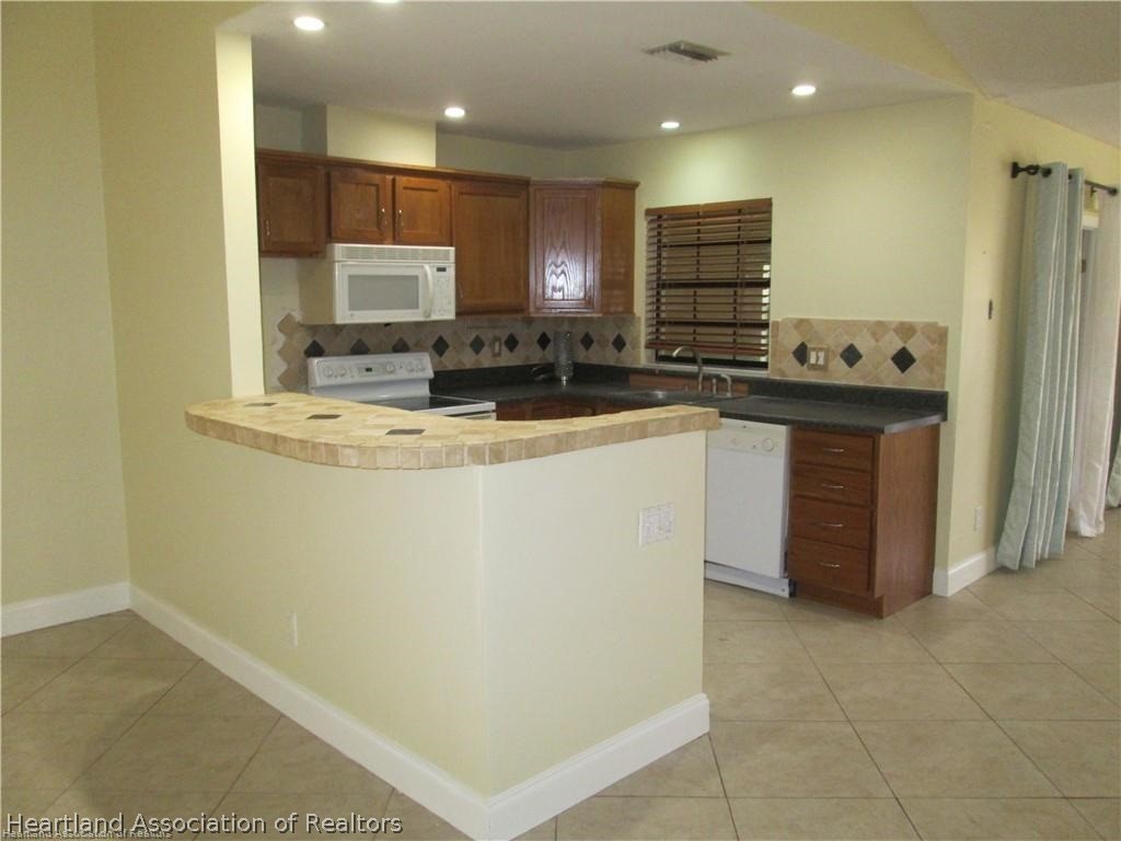3062 Orchid Road Lake Placid, FL 33852 - Photo 6 of 11 a kitchen with kitchen island granite countertop a sink and a refrigerator