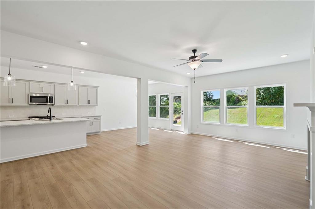308 Silverleaf Trail Bethlehem, GA 30620 - Photo 12 of 36 a view of an empty room with wooden floor and a kitchen