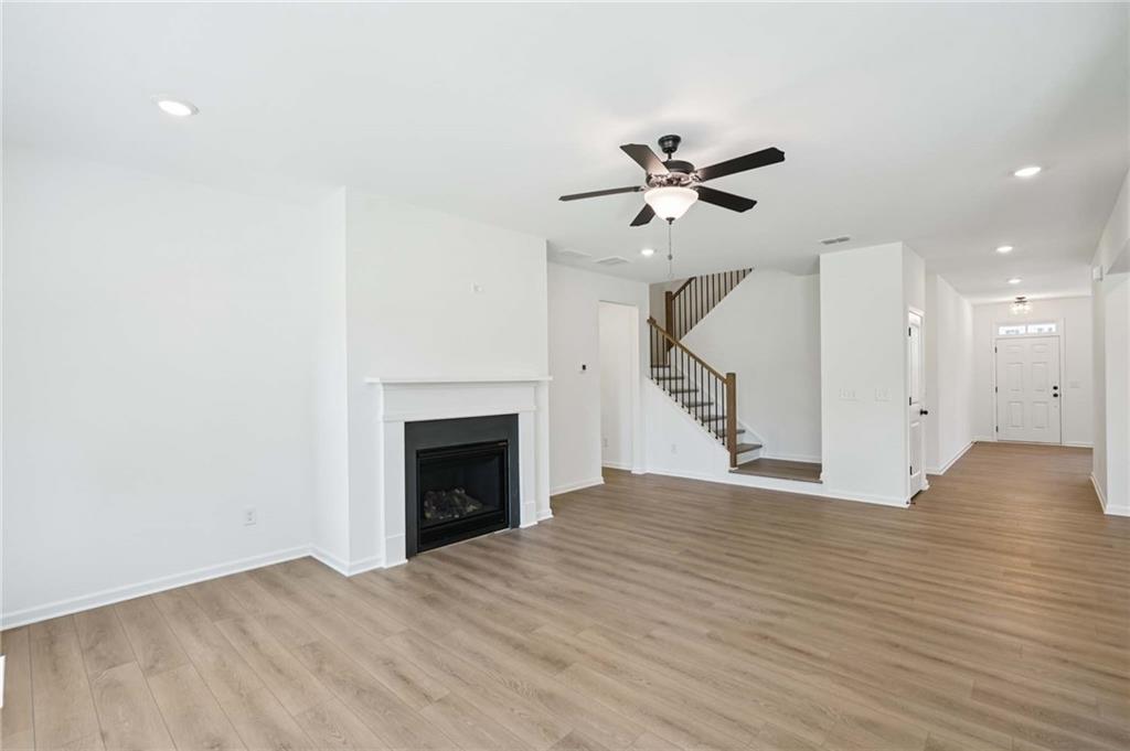 308 Silverleaf Trail Bethlehem, GA 30620 - Photo 9 of 36 a view of an empty room with wooden floor fireplace and a chandelier fan