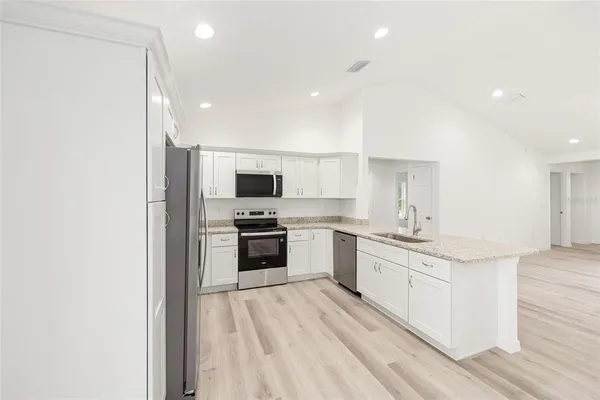 a kitchen with stainless steel appliances kitchen island granite countertop a stove a sink and white cabinets