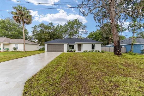 a front view of house with yard and trees in the background