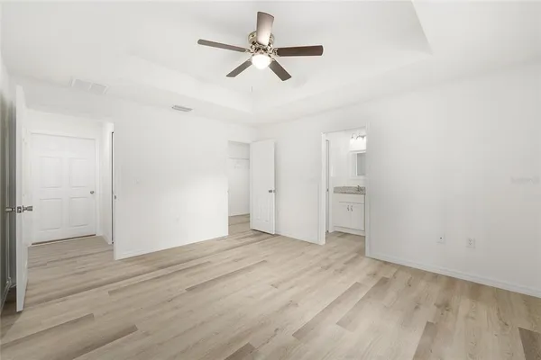 an empty room with wooden floor ceiling fan and windows