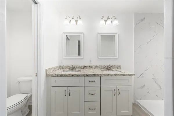 a bathroom with a granite countertop sink a toilet and a mirror
