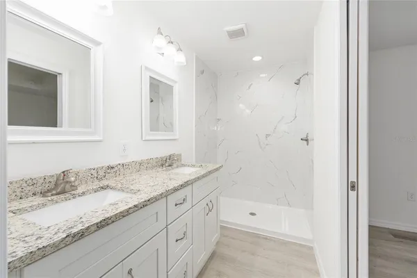 a bathroom with a granite countertop sink mirror and shower