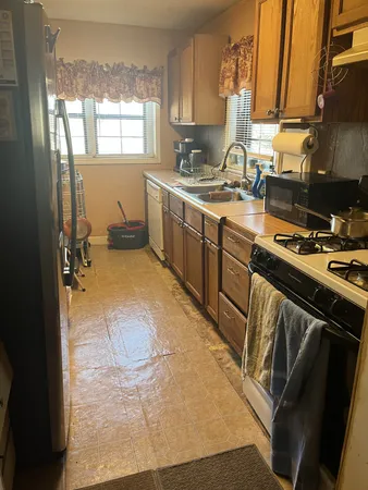a kitchen with a sink appliances cabinets and a window