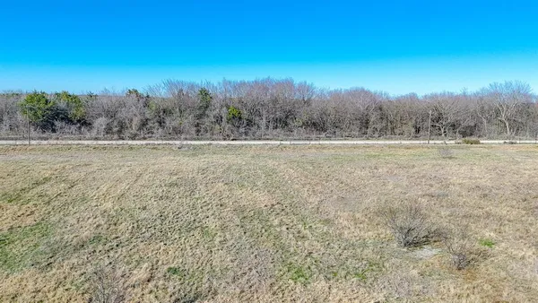 a view of dirt field with trees in background