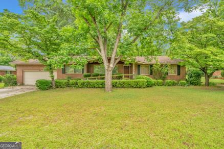 a front view of a house with a big yard and large trees