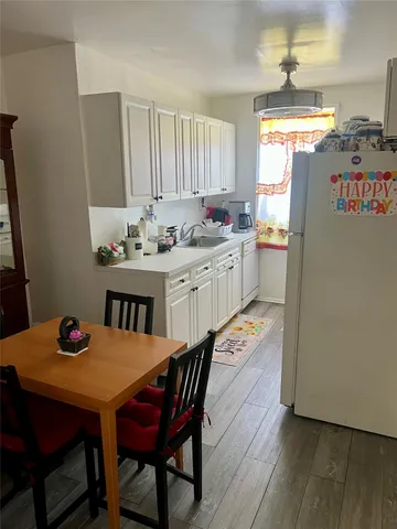 a kitchen with stainless steel appliances kitchen island granite countertop a dining table chairs and a refrigerator