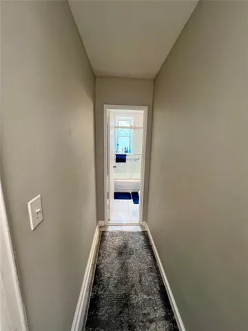 a view of a hallway with wooden floor and a bathroom