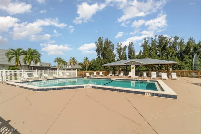 a view of swimming pool with outdoor seating and trees in the background