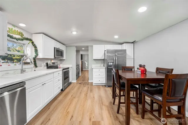 a kitchen with stainless steel appliances kitchen island granite countertop a sink cabinets and wooden floor