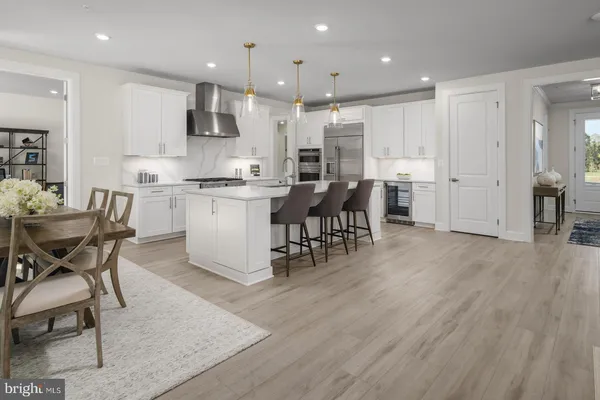 a kitchen with stainless steel appliances kitchen island granite countertop a table chairs stove and white cabinets