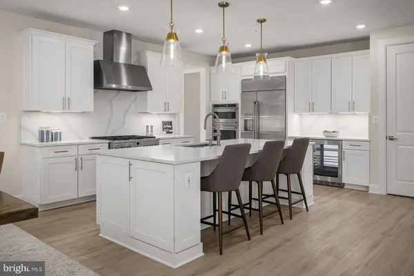 a kitchen with stainless steel appliances granite countertop a stove a refrigerator a kitchen island a sink a stove and white cabinets with wooden floor