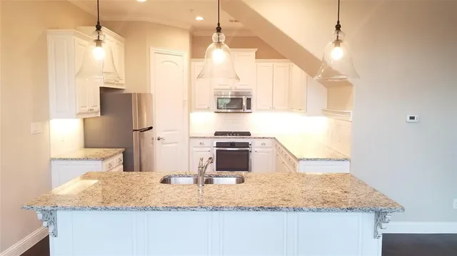 a kitchen with kitchen island granite countertop a sink and a refrigerator