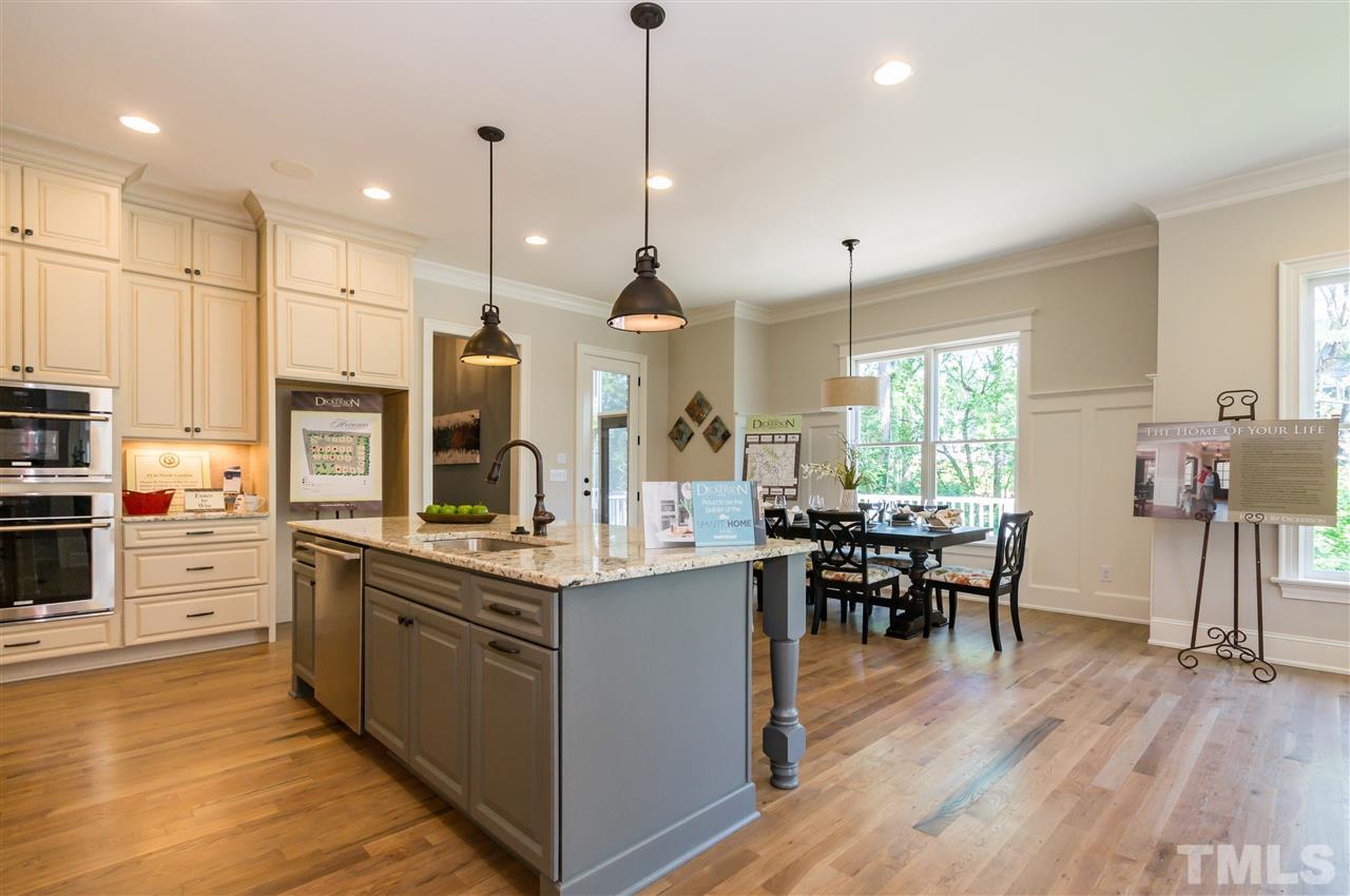 5208 Woodall Way, Unit 11 Raleigh, NC 27613 - Photo 9 of 25 a large kitchen with kitchen island a stove a sink a dining table and chairs