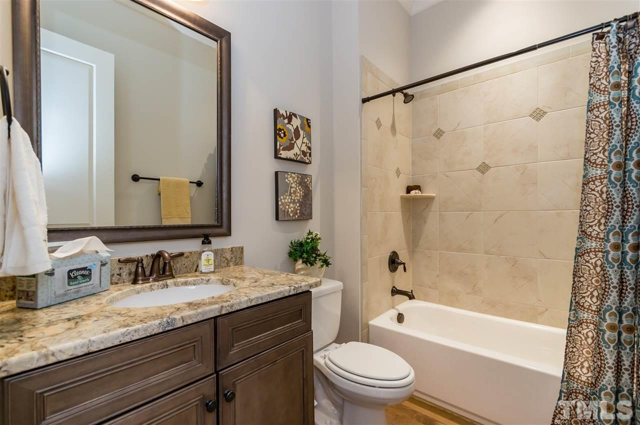 5208 Woodall Way, Unit 11 Raleigh, NC 27613 - Photo 10 of 25 a bathroom with a granite countertop sink a toilet a mirror a bathtub and shower