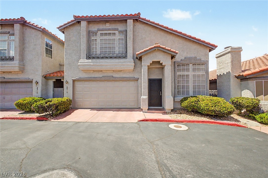 A terracotta-tiled roof crowns this stucco-finished home, complete with an integrated garage and desert-friendly landscaping.