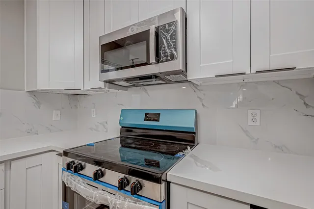 a kitchen with granite countertop a refrigerator and a stove top oven