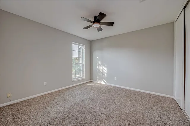 a view of an empty room and cabinet with a ceiling fan