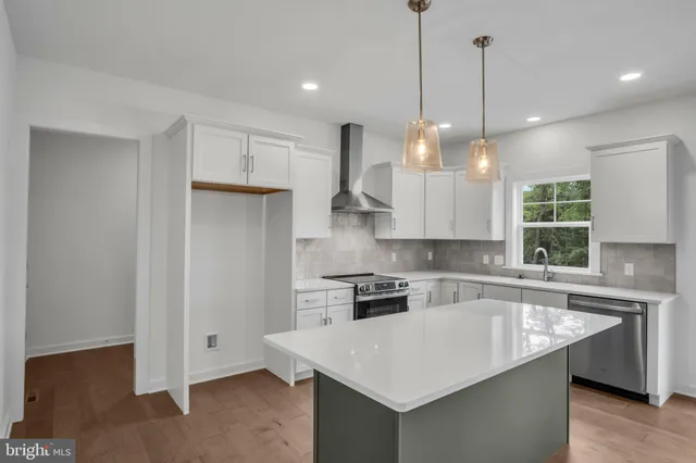 a kitchen with a sink a center island a stove cabinets and a window