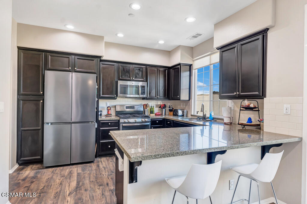 a kitchen with stainless steel appliances granite countertop a refrigerator stove microwave and sink