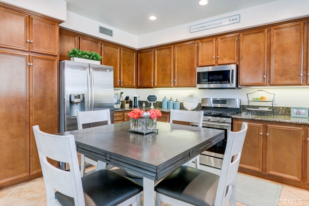 1 Agave Court Ladera Ranch, CA 92694 - Photo 9 of 23 a kitchen with stainless steel appliances a dining table a microwave a refrigerator and cabinets