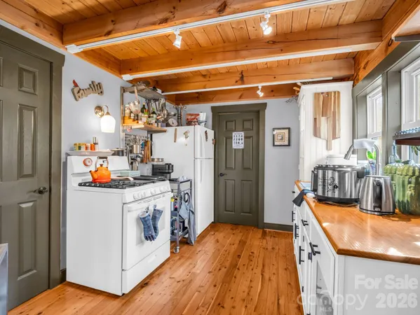 a utility room with stainless steel appliances wooden floor a stove and a refrigerator