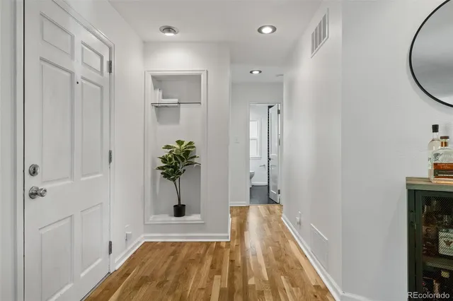 a view of a hallway with wooden floor and a bathroom