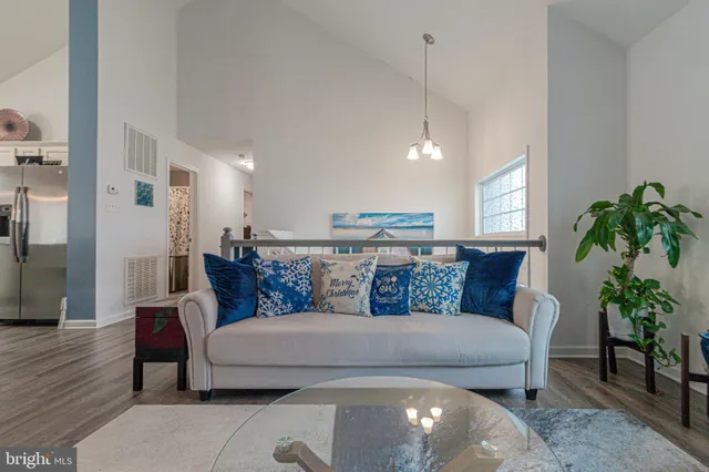 a living room with furniture kitchen view and a chandelier