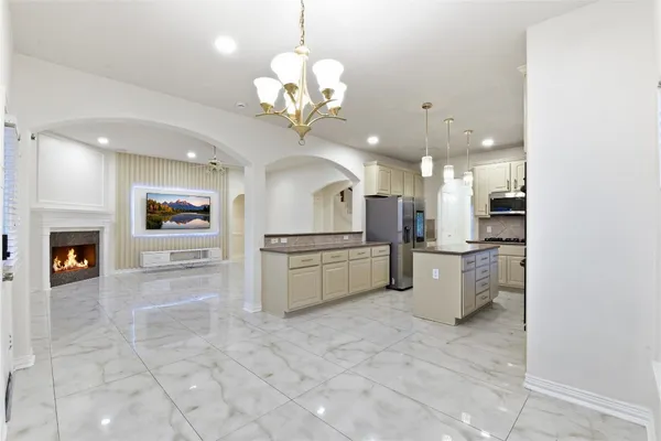 a large kitchen with a refrigerator a stove top oven a sink and a chandelier