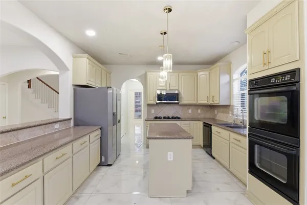 a kitchen with stainless steel appliances granite countertop a refrigerator a sink dishwasher a stove oven and white cabinets with wooden floor