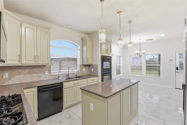 a kitchen with stainless steel appliances granite countertop a sink a stove and a wooden cabinets