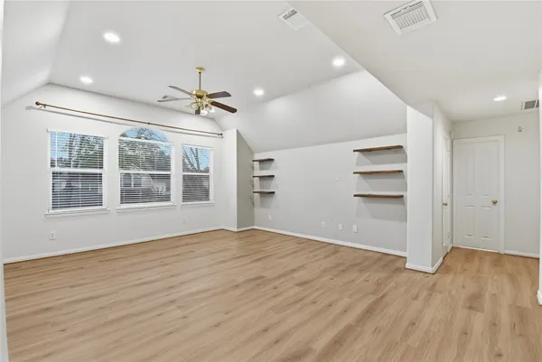 a view of an empty room with a window and wooden floor