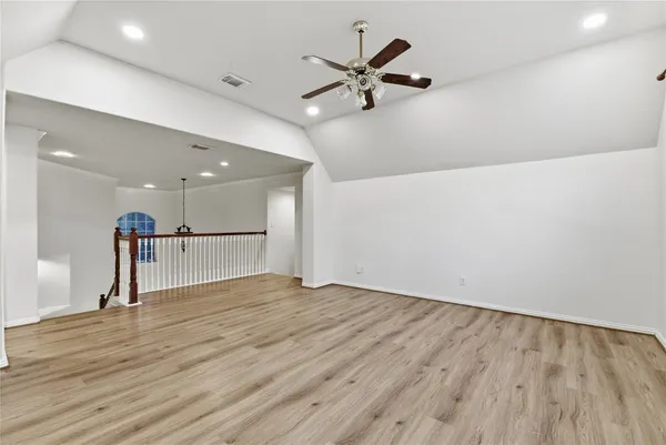 an empty room with wooden floor and ceiling fan