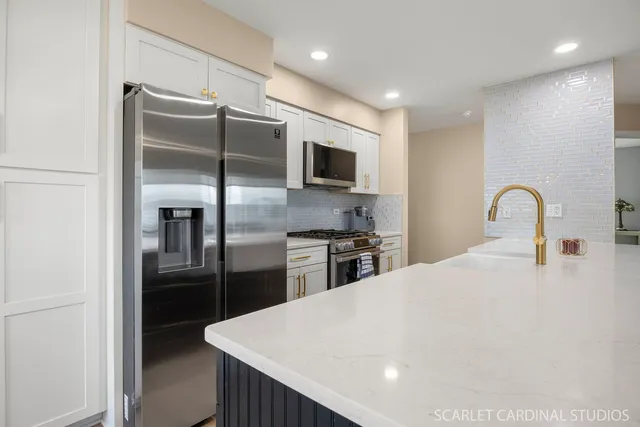 a kitchen with stainless steel appliances kitchen island granite countertop a refrigerator a stove a sink and a refrigerator