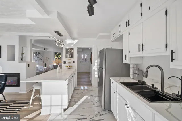 a kitchen with stainless steel appliances a sink a stove a refrigerator cabinets and a dining table