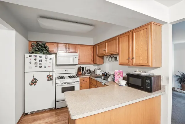 a kitchen with a refrigerator a stove a sink dishwasher and wooden cabinets with wooden floor