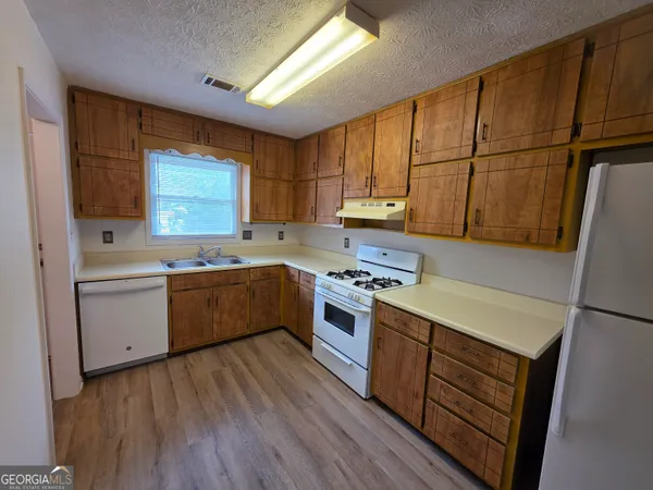 a kitchen with stainless steel appliances a sink cabinets and wooden floor