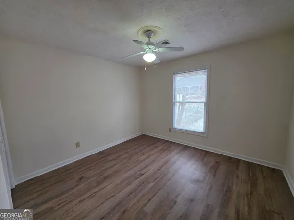 a view of an empty room with wooden floor and a window