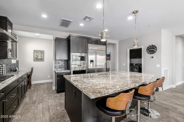 a living room with furniture kitchen area and a wooden floor