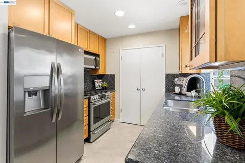 a kitchen with stainless steel appliances granite countertop a refrigerator a stove and a sink