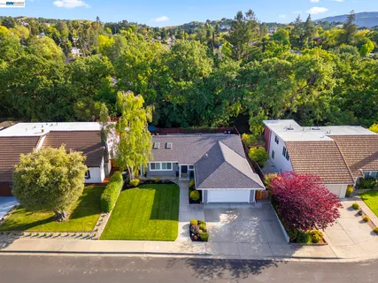 an aerial view of a house with swimming pool and large trees