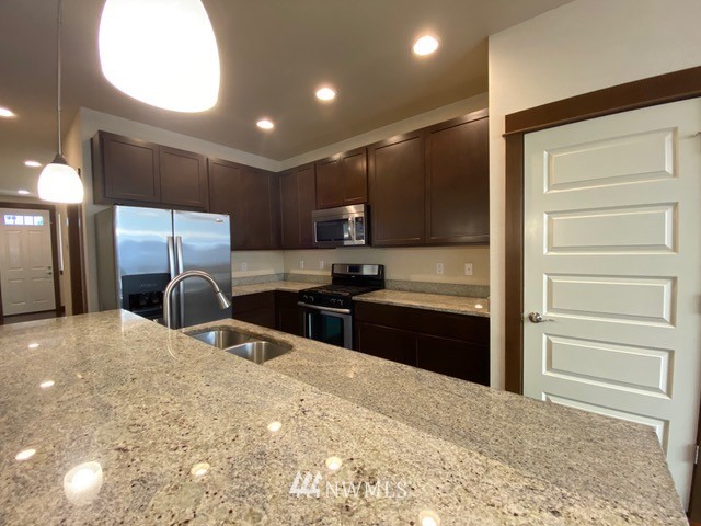 419 203rd Place Southeast Bothell, WA 98012 - Photo 18 of 30 a kitchen with stainless steel appliances kitchen island granite countertop a refrigerator and a sink