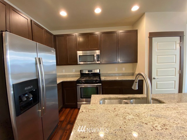 419 203rd Place Southeast Bothell, WA 98012 - Photo 26 of 30 a kitchen with stainless steel appliances granite countertop a refrigerator a stove and a sink with wooden floor