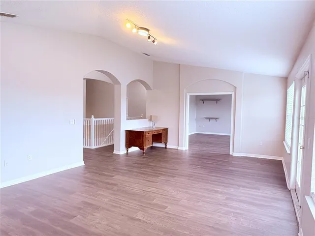 a view of an empty room with a window and wooden floor