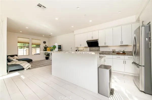 a living room with stainless steel appliances kitchen island granite countertop a sink a stove and a refrigerator with wooden floor