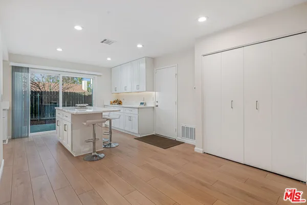 a kitchen with a refrigerator and white cabinets