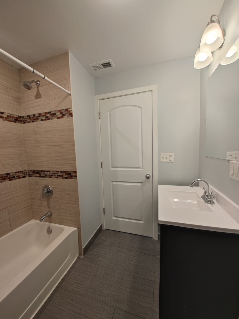 4201 West Division Street, Unit 2 Chicago, IL 60651 - Photo 7 of 7 a bathroom with a tub a sink and a mirror